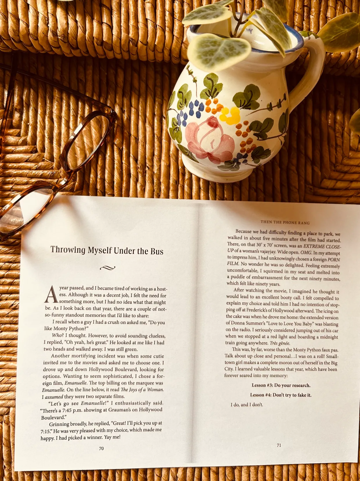 An open book — Throwing Myself Under the Bus chapter — beside a floral pitcher and reading glasses
