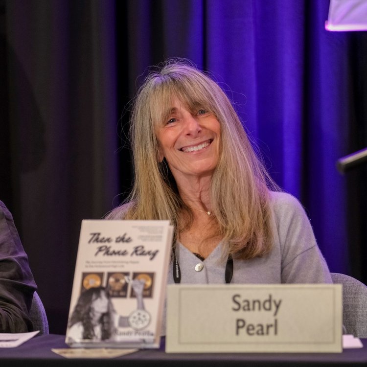 Sandy Pearl smiling on the Nonfiction Author Panel with her book Then the Phone Rang displayed beside her name card